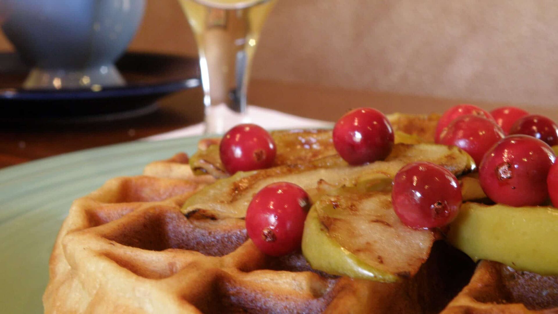 Warm hazelnut waffle with apples and currants and a glass of orange juice