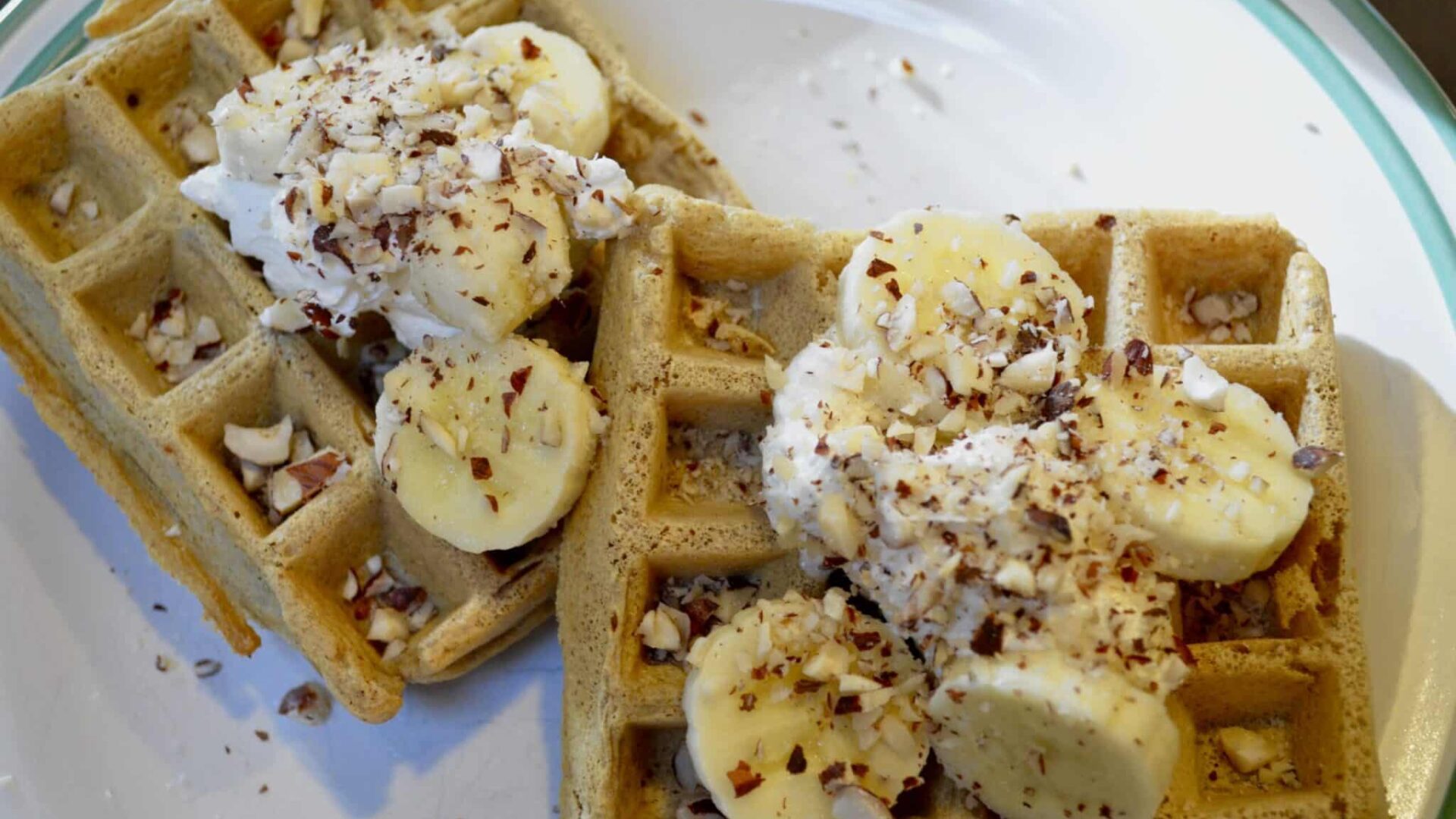 Hazelnut Waffles on a white plate with whipped cream and bananas