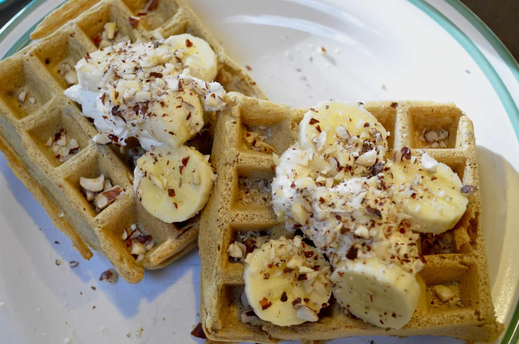 Hazelnut Waffles on a white plate with whipped cream and bananas