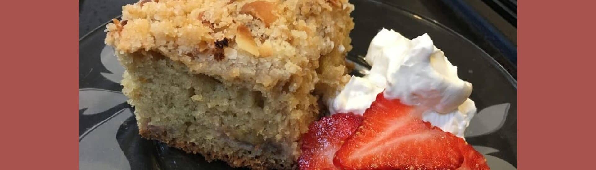 a piece of strawberry rhubarb coffee cake with fresh strawberries and whipped cream