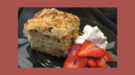 a piece of strawberry rhubarb coffee cake with fresh strawberries and whipped cream