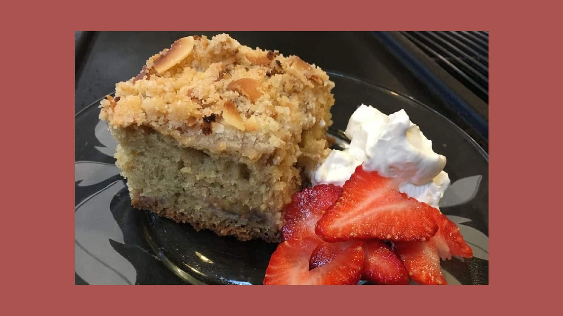 a piece of strawberry rhubarb coffee cake with fresh strawberries and whipped cream