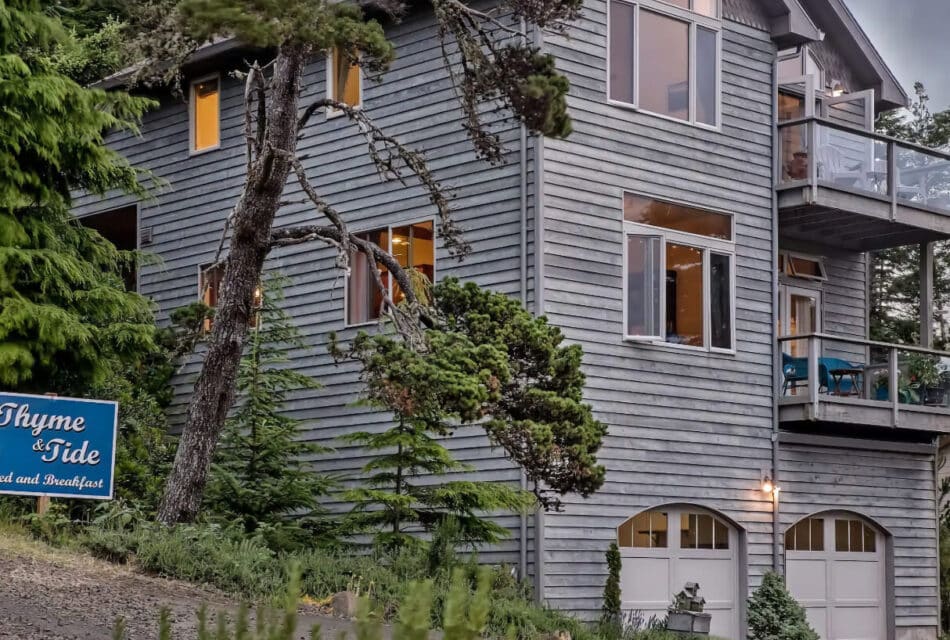 External view of property painted gray surrounded by large green trees