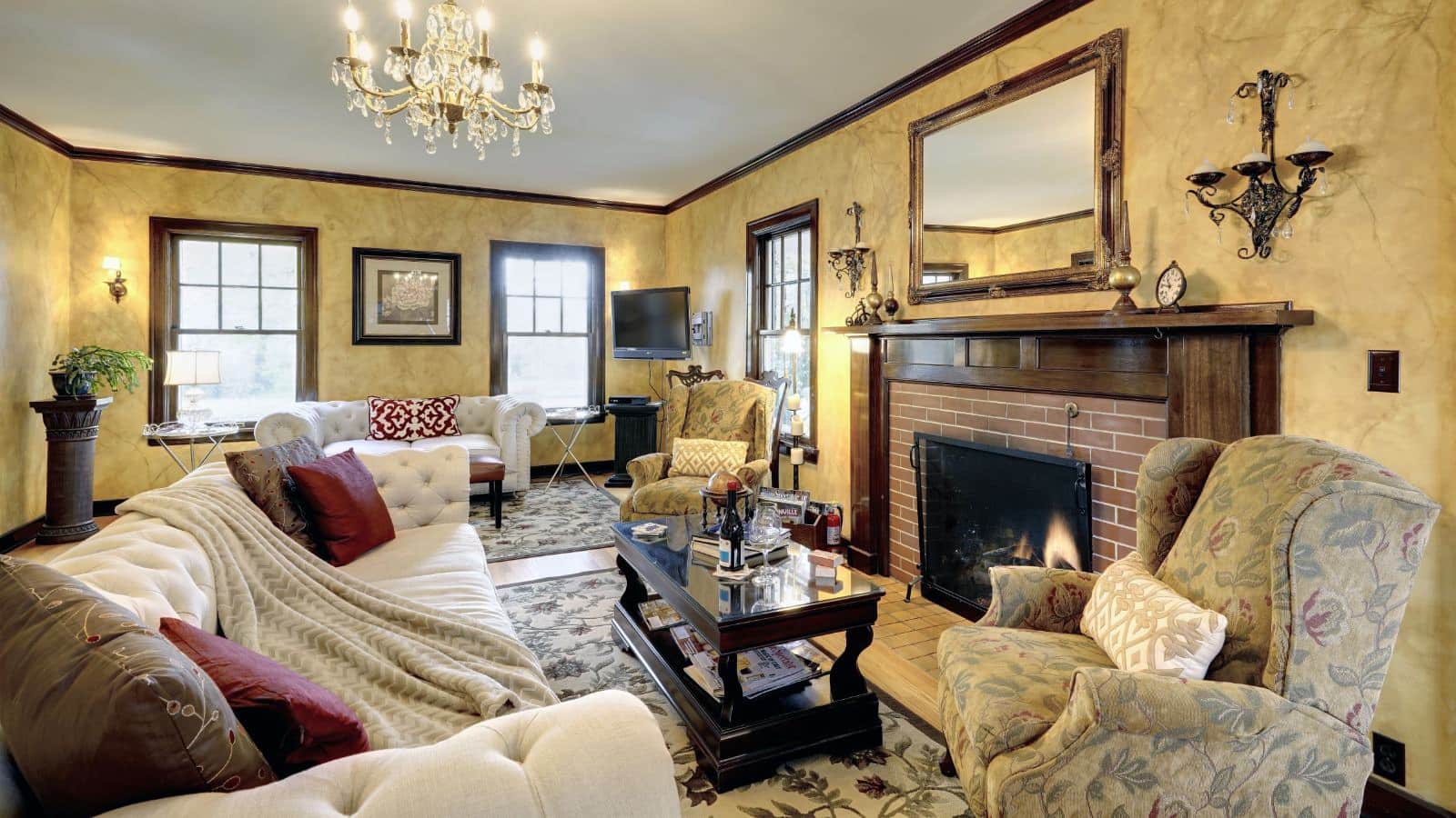 Living room with light colored walls, hardwood flooring, area rugs, white upholstered sofas, multicolored upholstered chairs, and fireplace