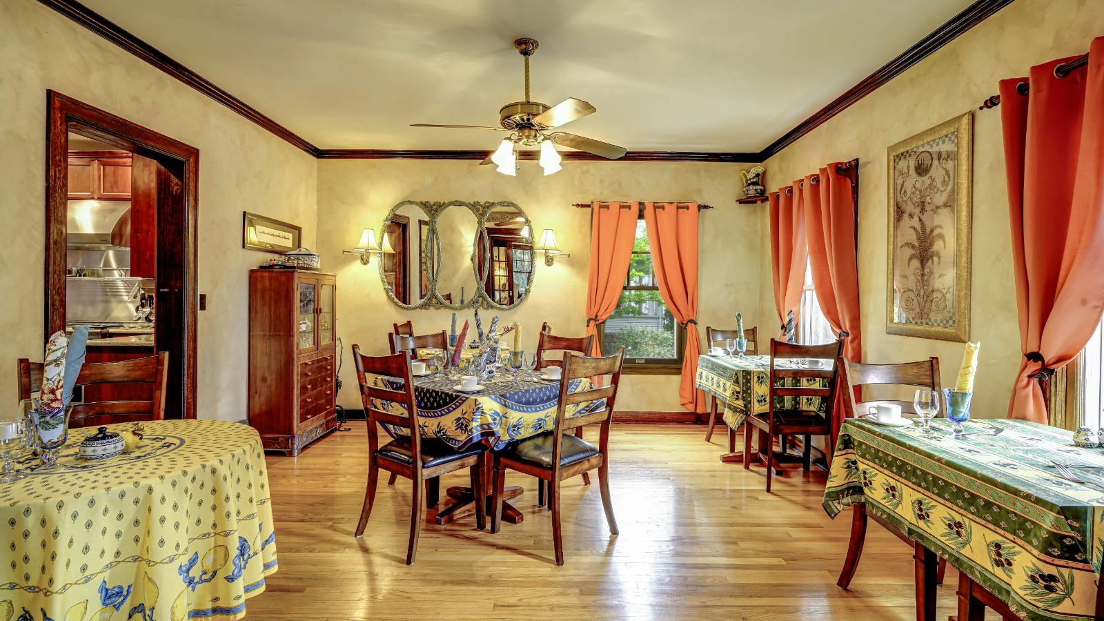 Dining room with light colored walls, hardwood flooring, multiple wooden tables with chairs, and china hutch