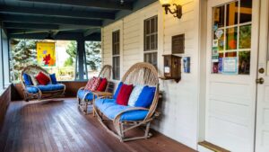 Porch with custom wooden chairs and porch swing with red white and blue pillows and cushions
