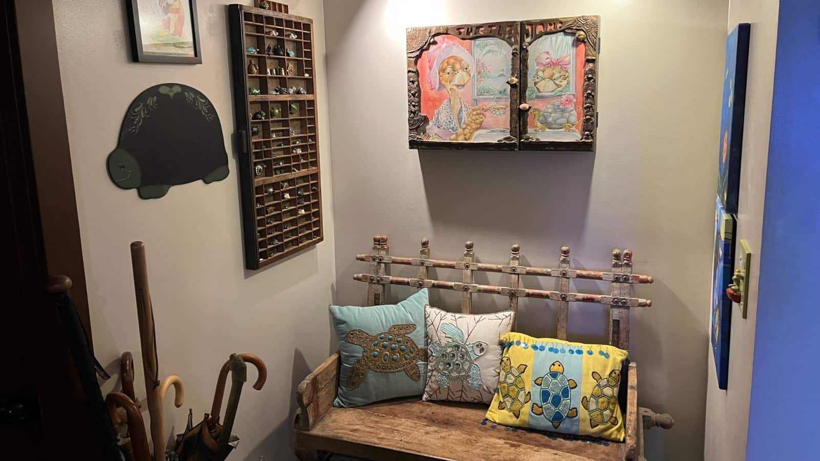 Nook with light colored wall, wooden bench with turtle pillows, and wall art featuring turtles