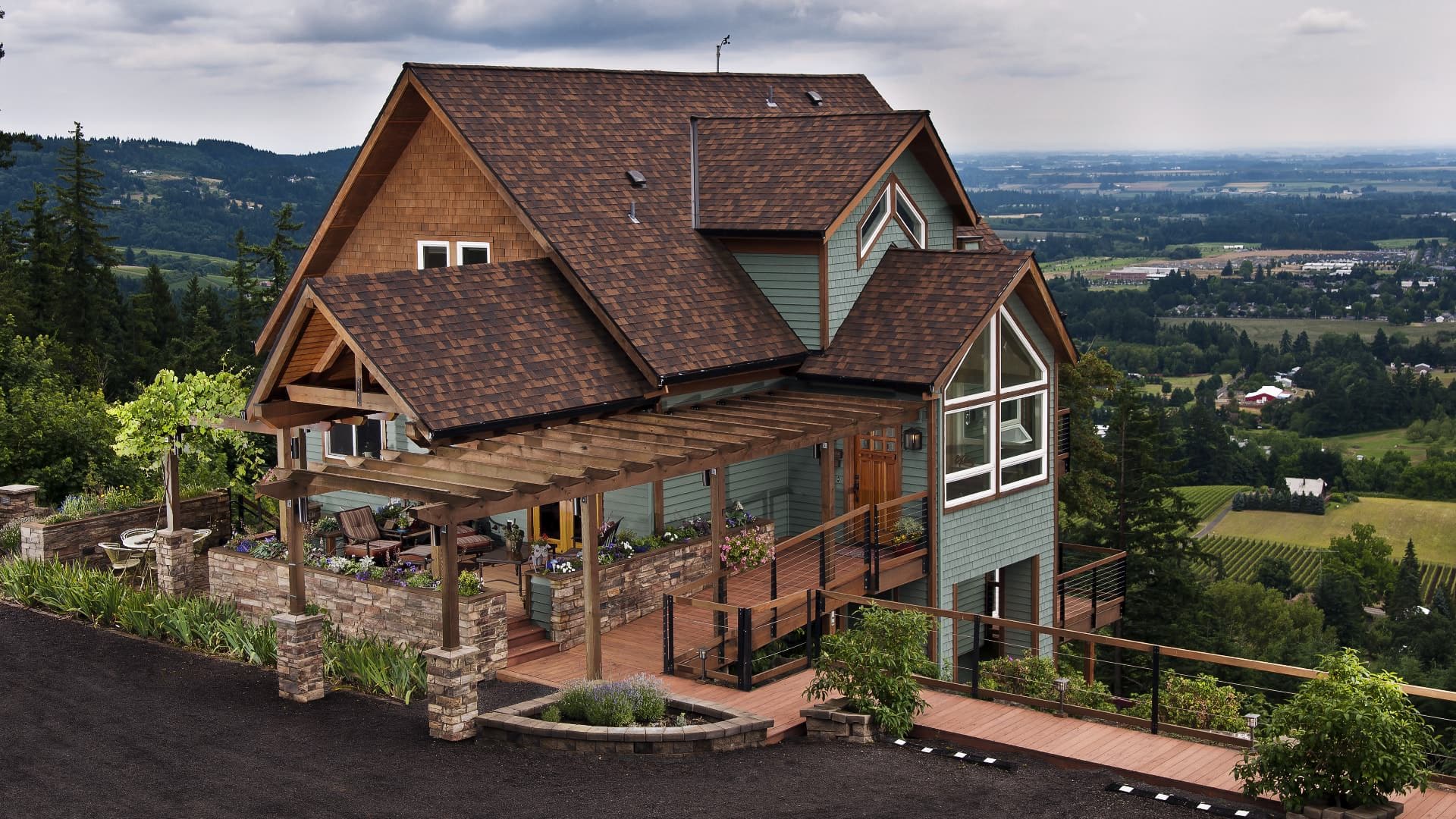 Exterior view of property painted light sage green with brown trim on the side of a hill overlooking farms and properties