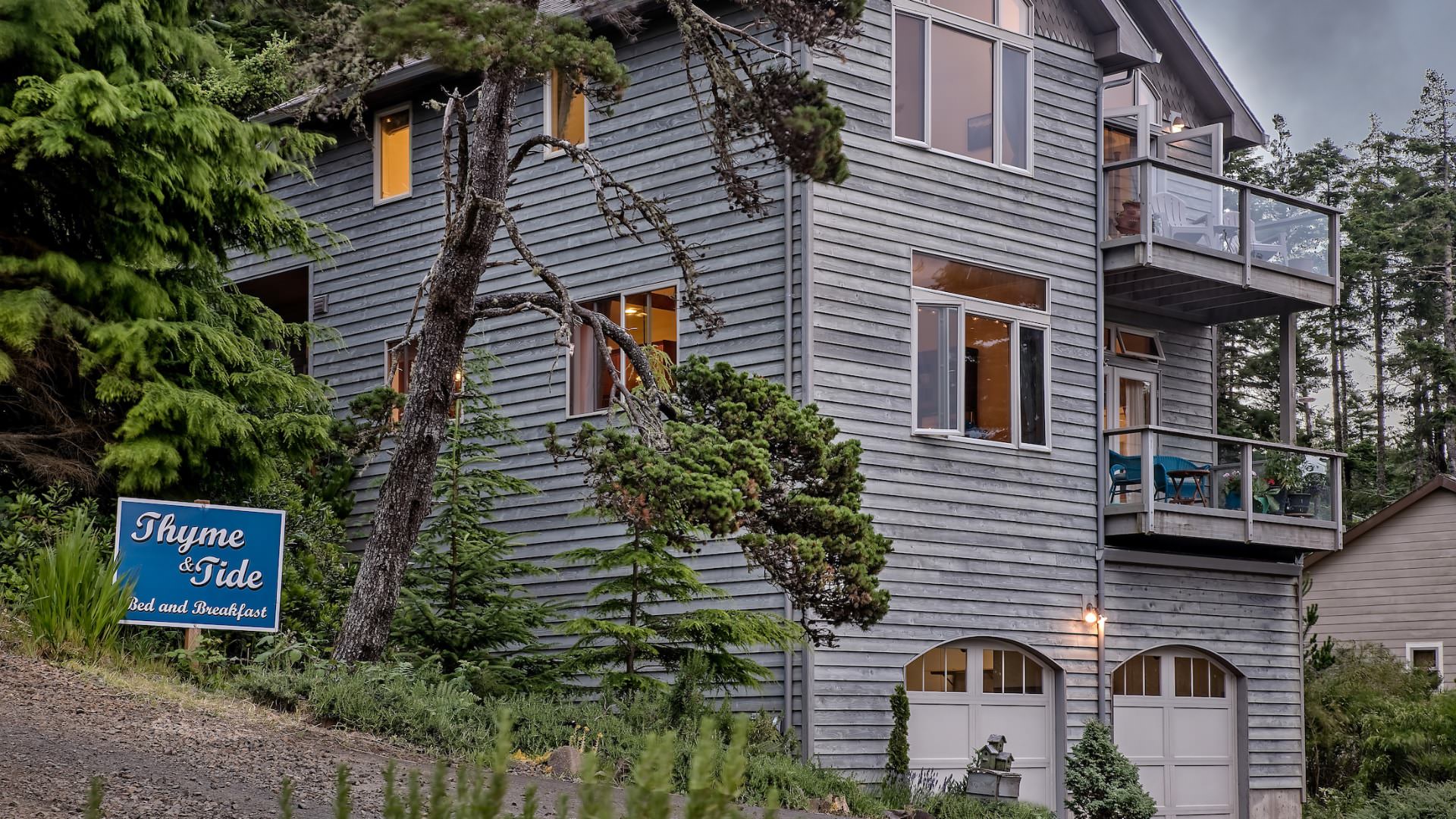 External view of property painted gray surrounded by large green trees