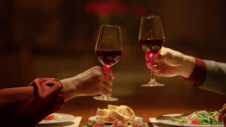 Two arms, each with a glass of wine in hand, sending up cheers